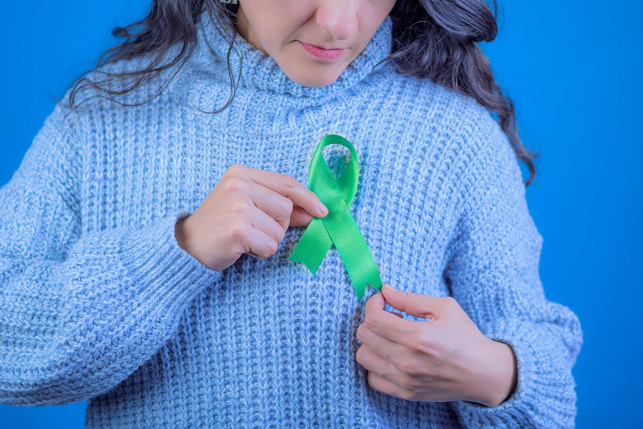 Woman putting on liver cancer awareness ribbon.